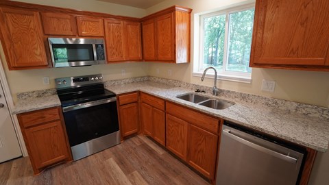 A kitchen with wooden cabinets and a granite countertop.