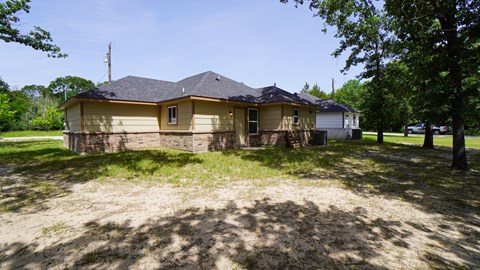 A house with a brown roof and a white garage door is surrounded by trees.