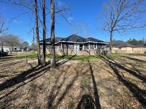 A house with a black roof is surrounded by bare trees.