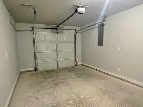 A garage with a white door and a concrete floor.