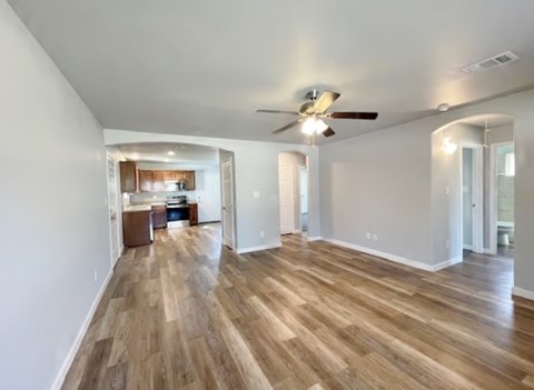 A spacious room with wooden flooring and a ceiling fan.