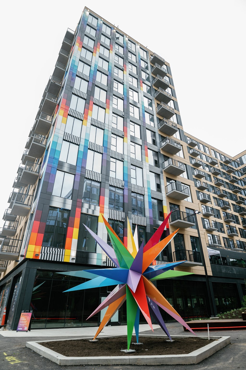 A large, colorful, star-shaped sculpture is in front of a tall, colorful building.