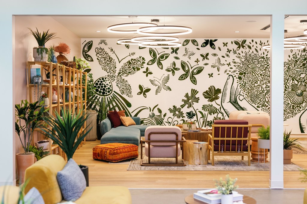 A living room with a large mural of plants on the wall.