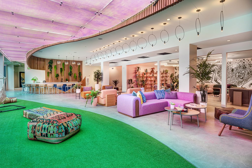 A modern living room with a green carpet and a variety of furniture.