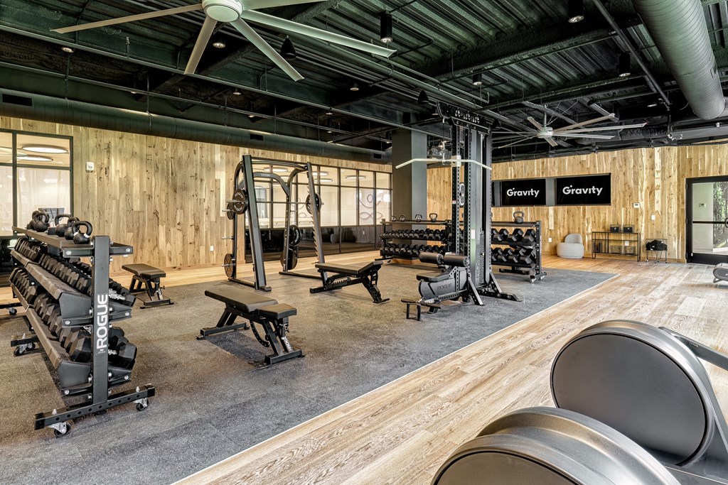 A gym with a variety of equipment including weight benches and dumbbells.