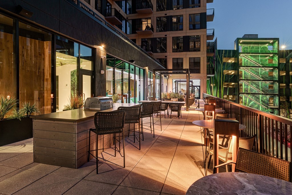 A patio with tables and chairs is lit up at dusk.