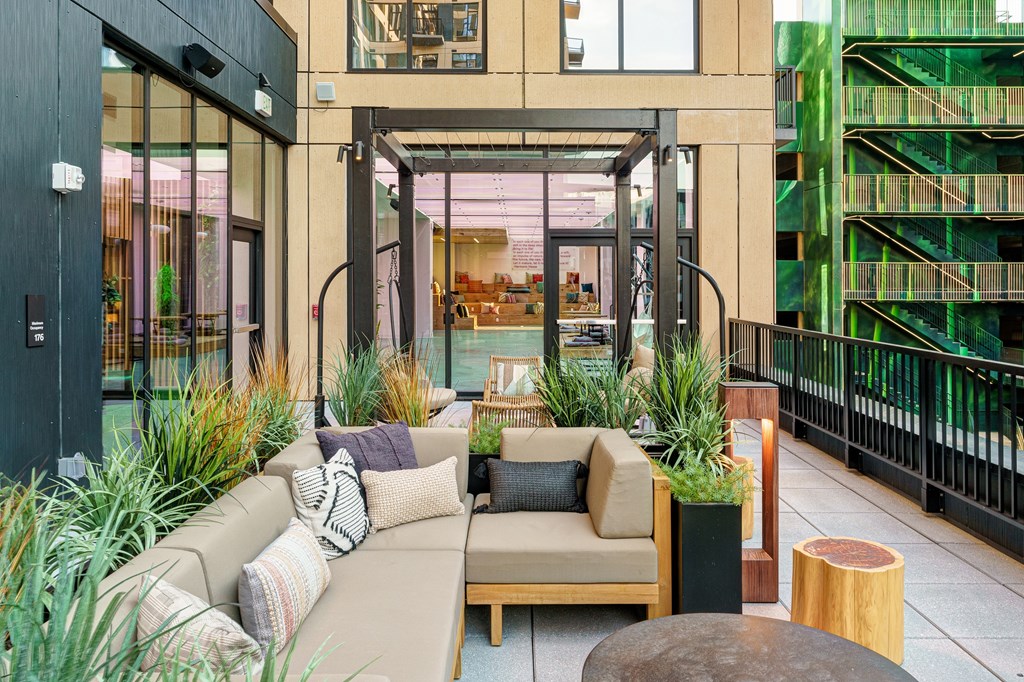 A modern outdoor seating area with a couch, pillows, and plants.