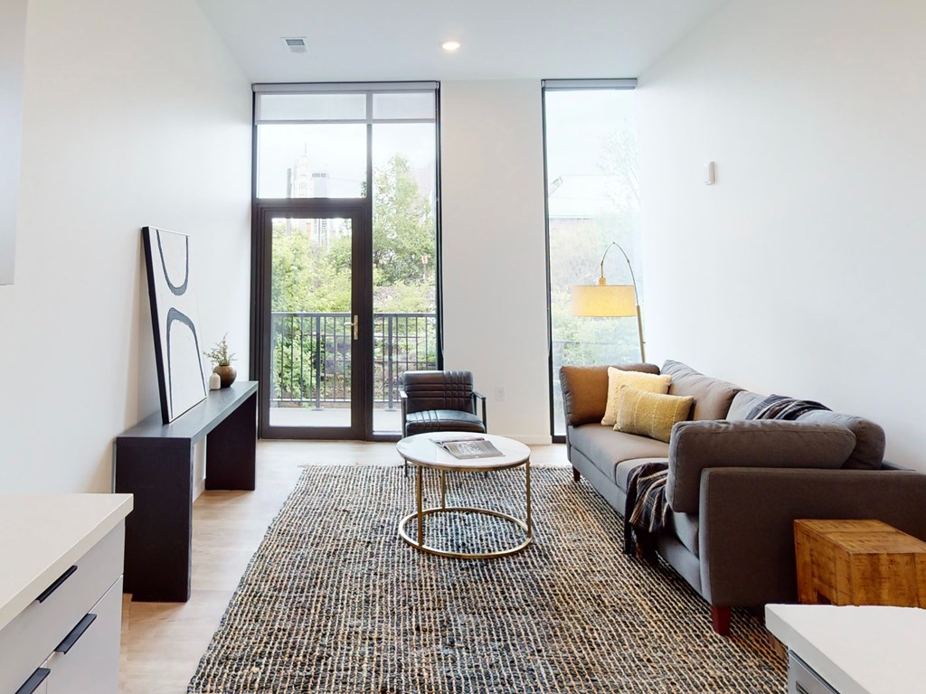 A modern living room with a grey couch and a white coffee table.