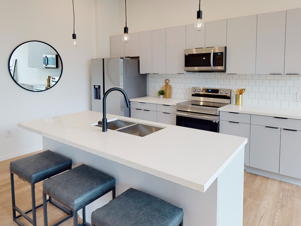 A kitchen with a white countertop and a black fridge.