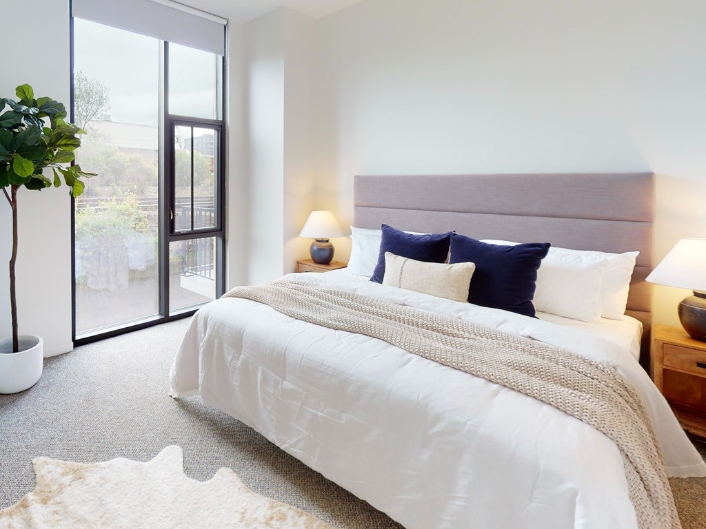 A bedroom with a large bed and a potted plant.