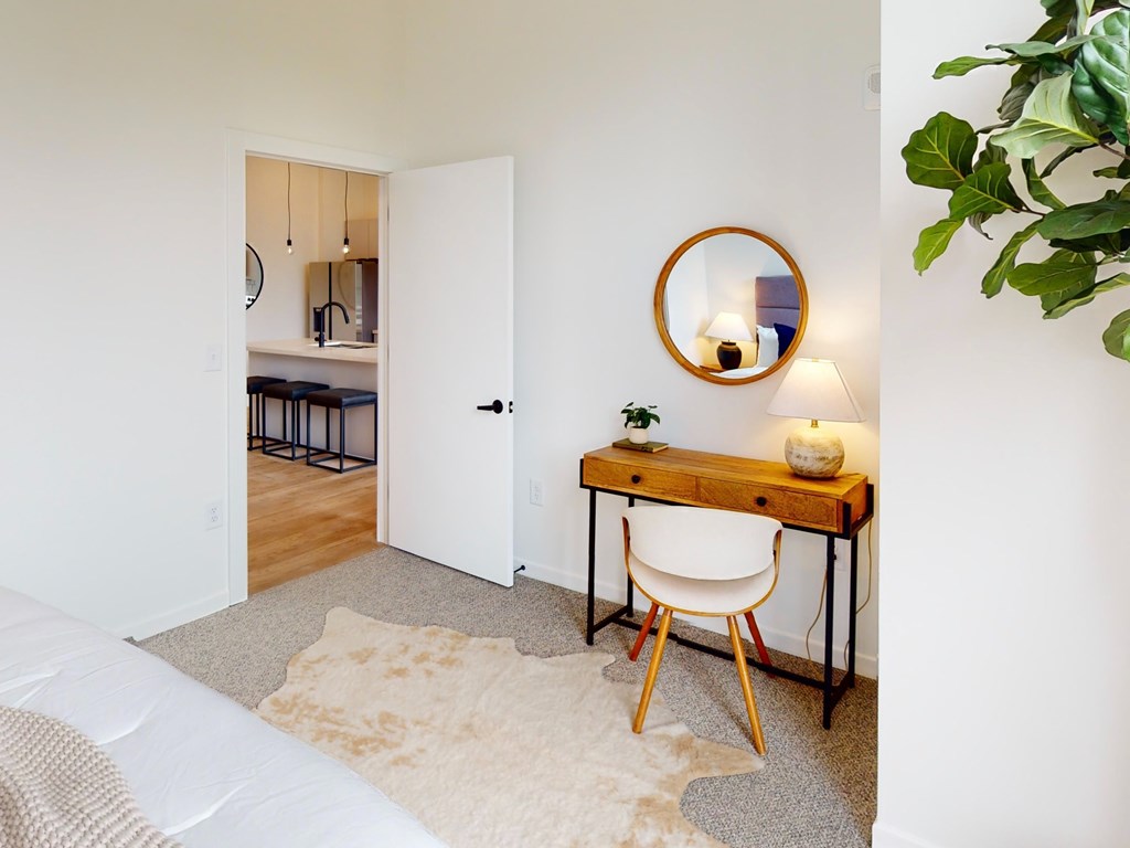 A white bedroom with a desk and chair.