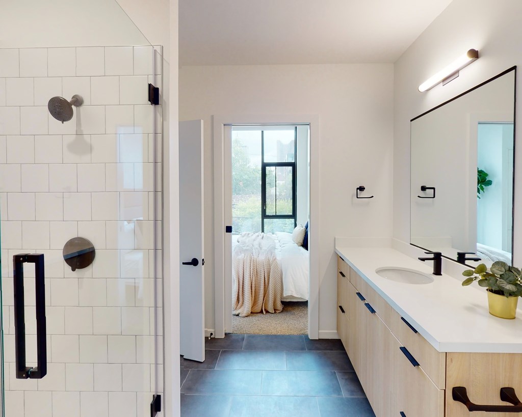 A bathroom with a white tiled shower and a white sink.