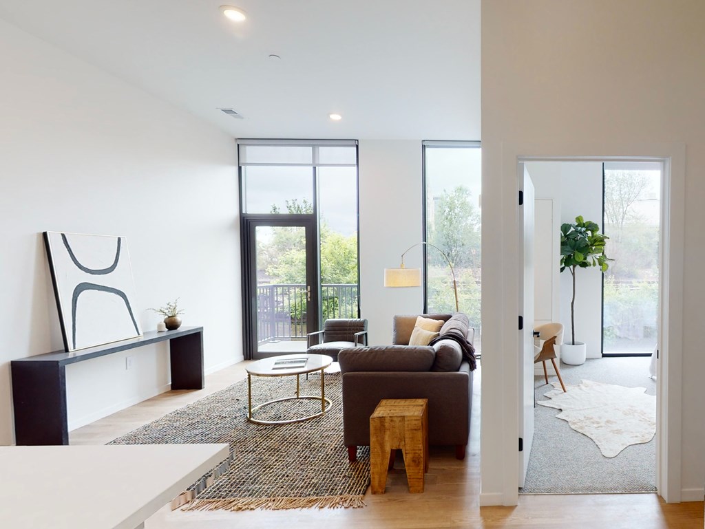 A modern living room with a large window and a view of a fence and trees.