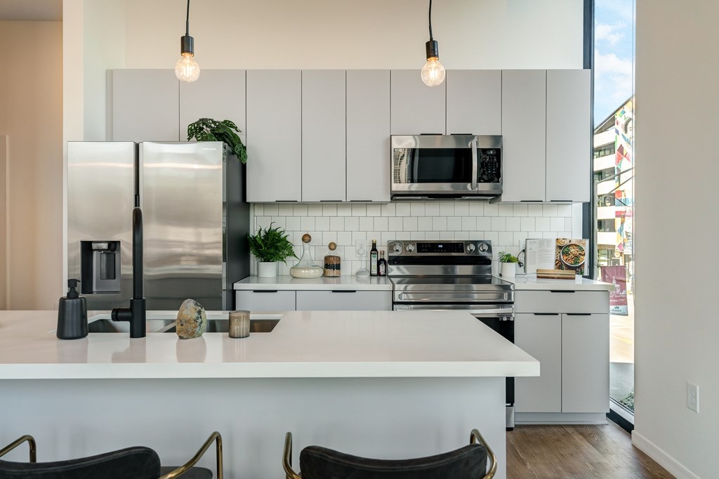 A modern kitchen with a white island and stainless steel appliances.