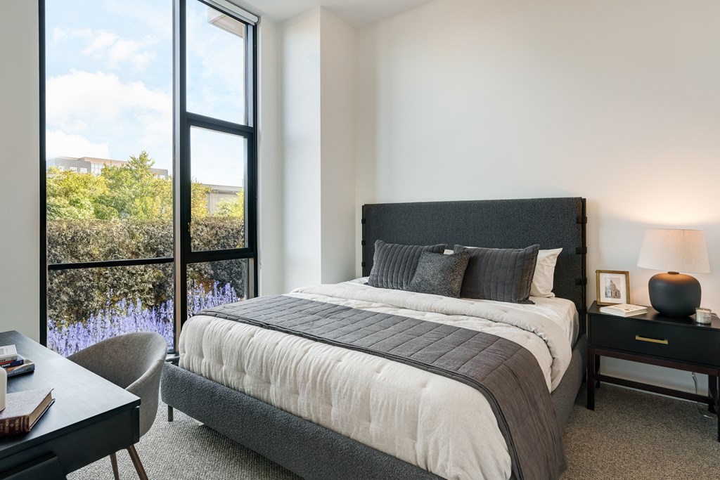 A bedroom with a large bed and a chair by the window.