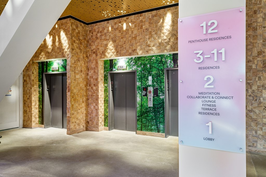 A sign in a hallway indicates the different floors of a building, from lobby to penthouse residences.