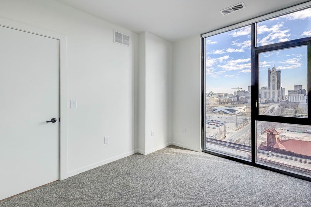 A room with a view of the city through a large window.
