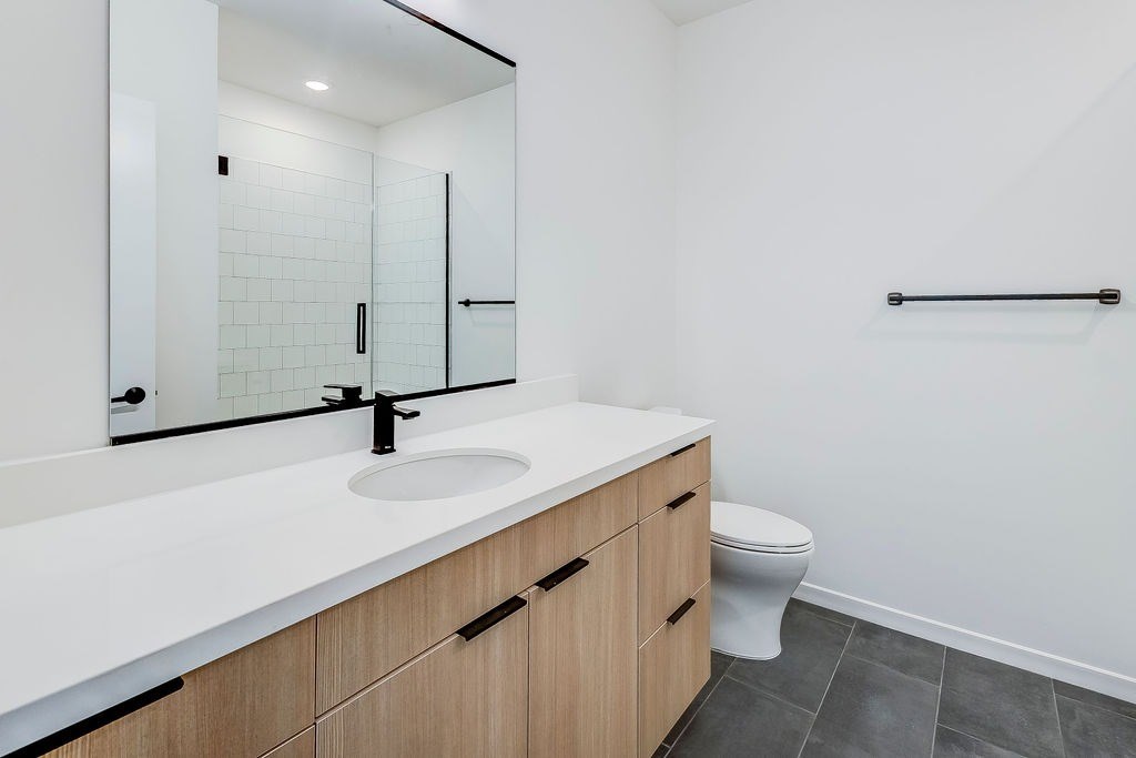 A white sink with a black faucet is on a countertop in a bathroom.