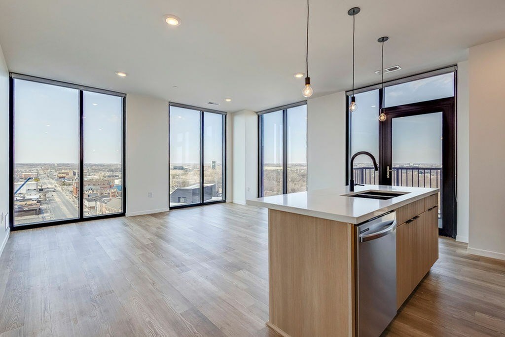 A modern kitchen with wooden floors and a large window overlooking the city.