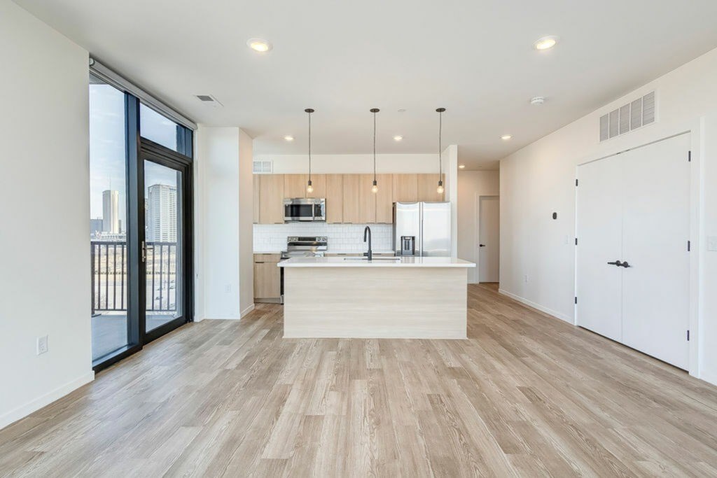 A modern kitchen with a wooden floor and white walls.