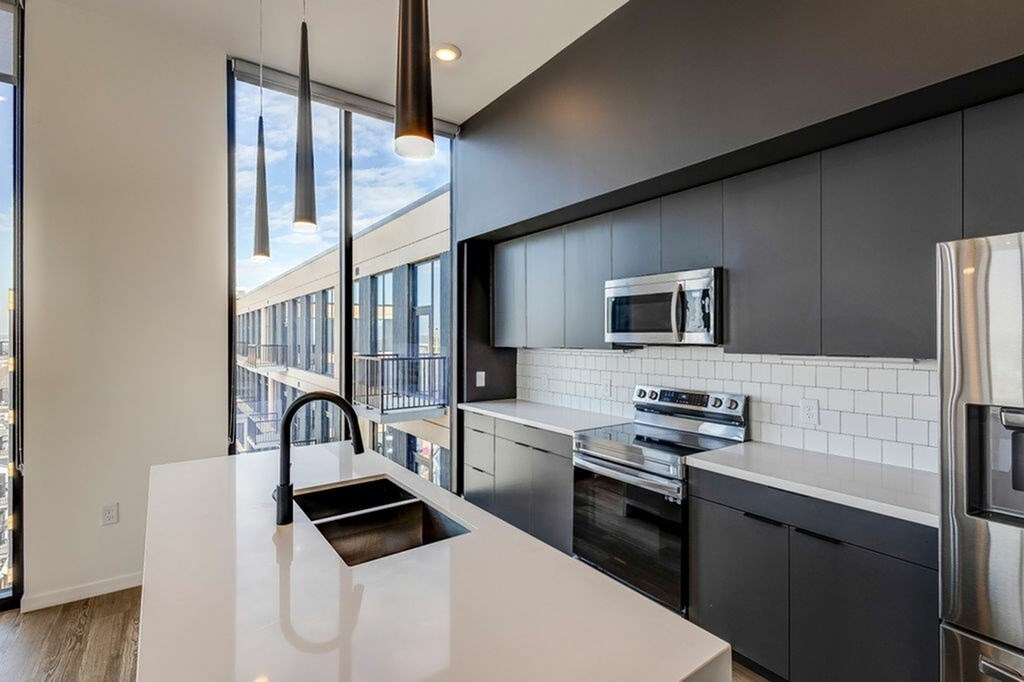 A modern kitchen with a white countertop and stainless steel appliances.