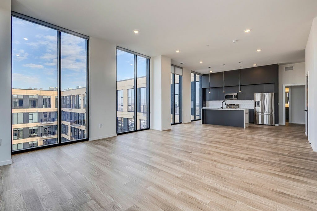 A spacious living room with wooden flooring and large windows.