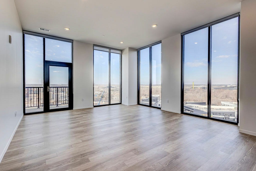 A spacious room with large windows and wooden flooring.