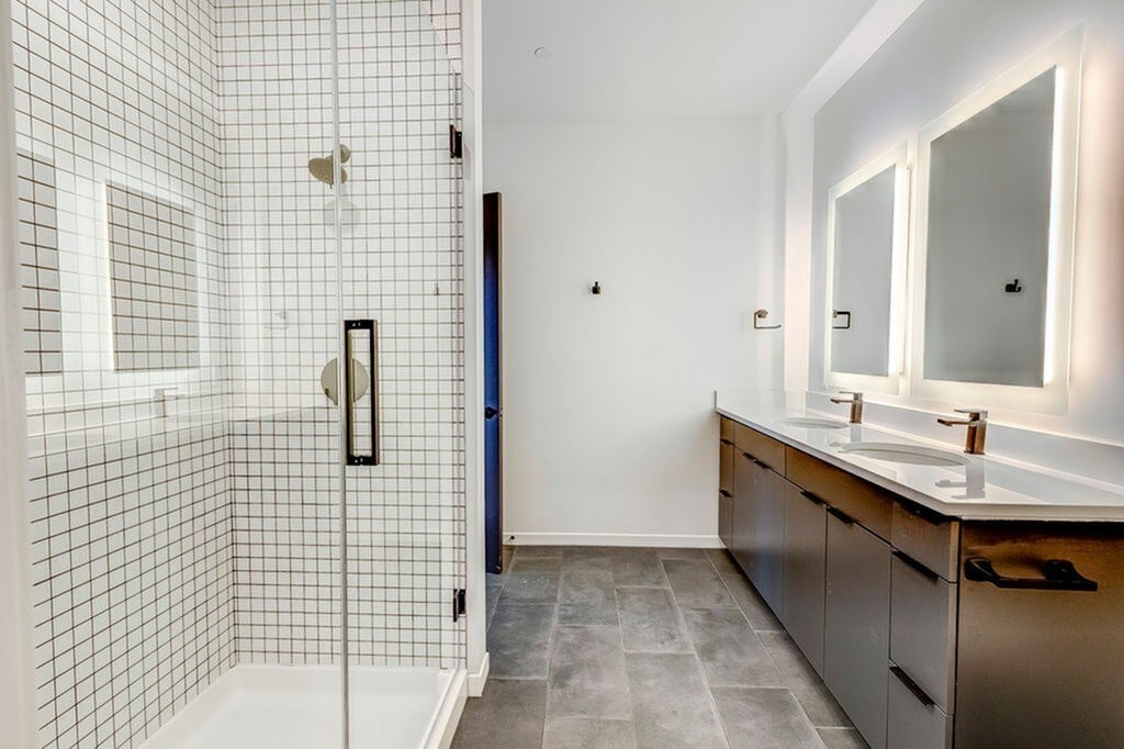 A bathroom with a walk-in shower and double sink vanity.