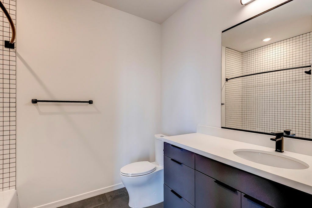 A white toilet sits in a bathroom next to a sink.