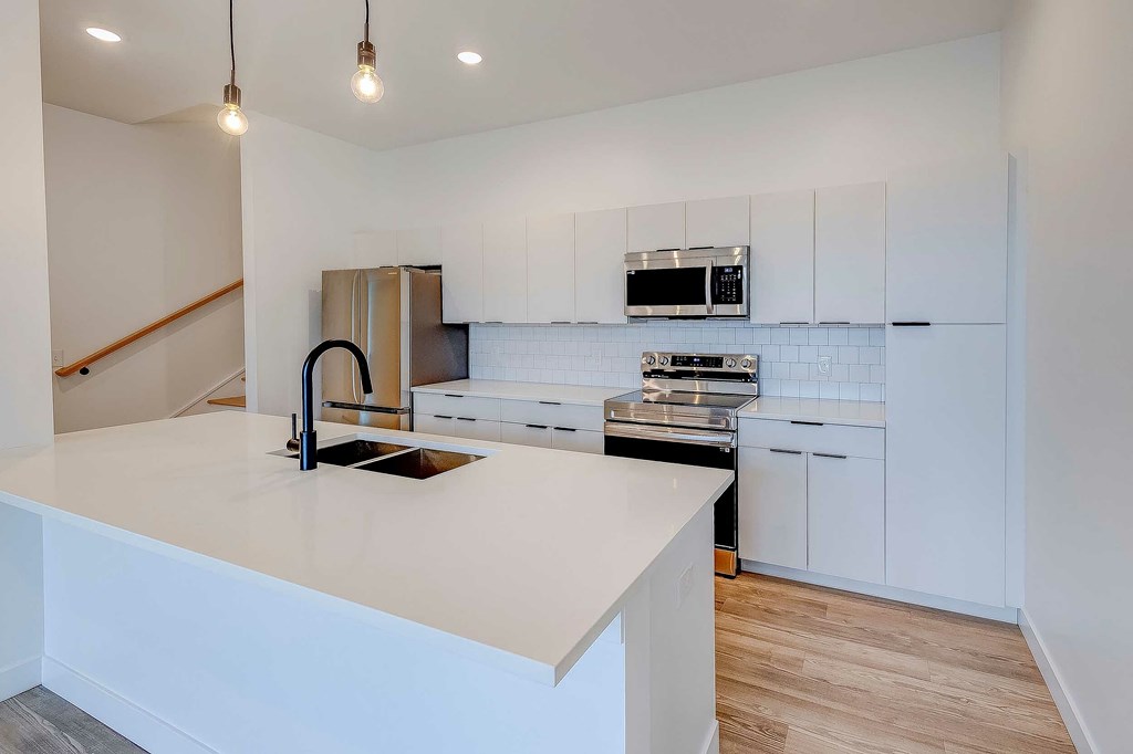 A kitchen with a white countertop and a black faucet.