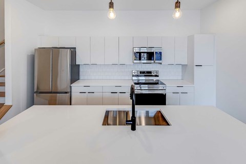 A modern kitchen with a stainless steel refrigerator and a white countertop.