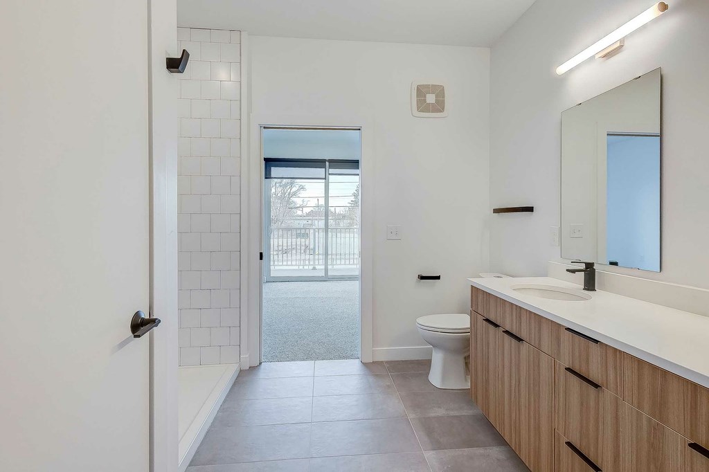 A bathroom with a toilet, sink, and mirror.
