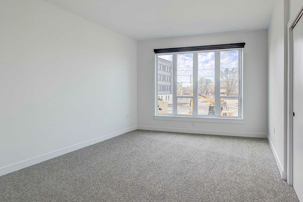 A room with a large window and a grey carpet.