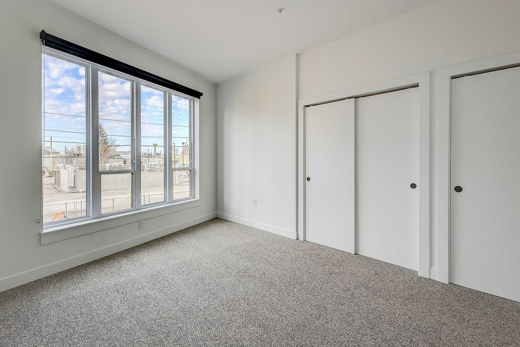 A room with a large window and a carpeted floor.