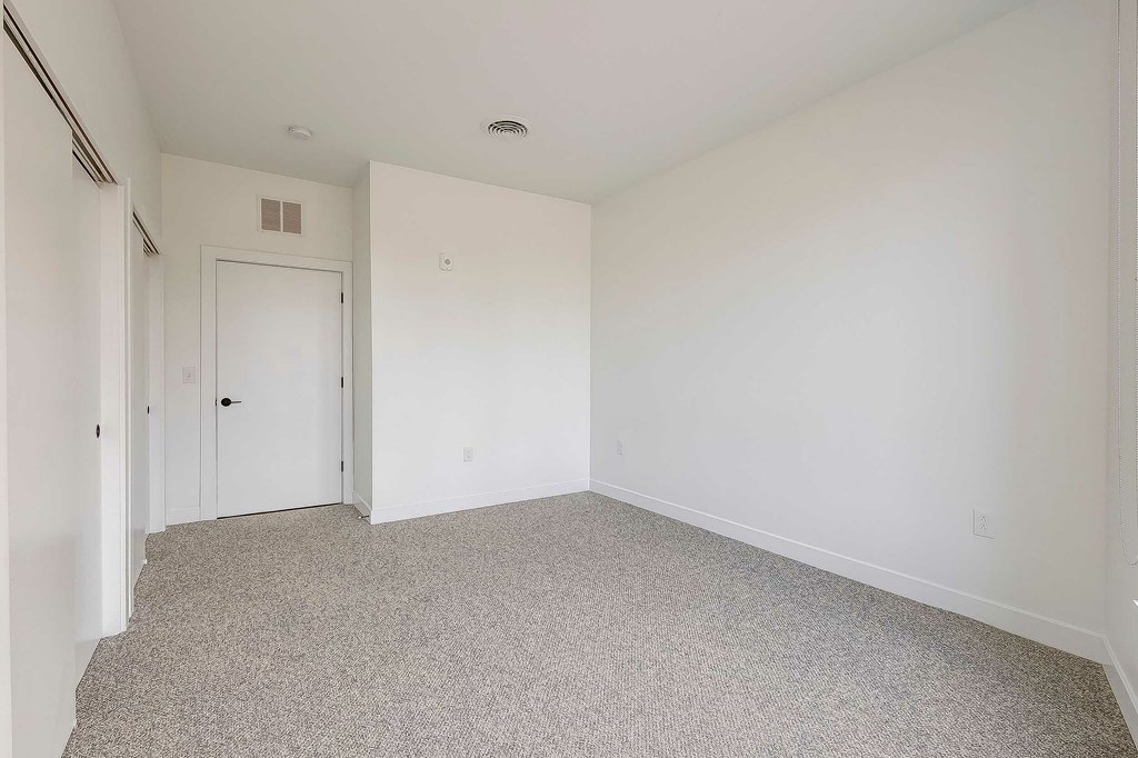 A room with a carpeted floor and a door.