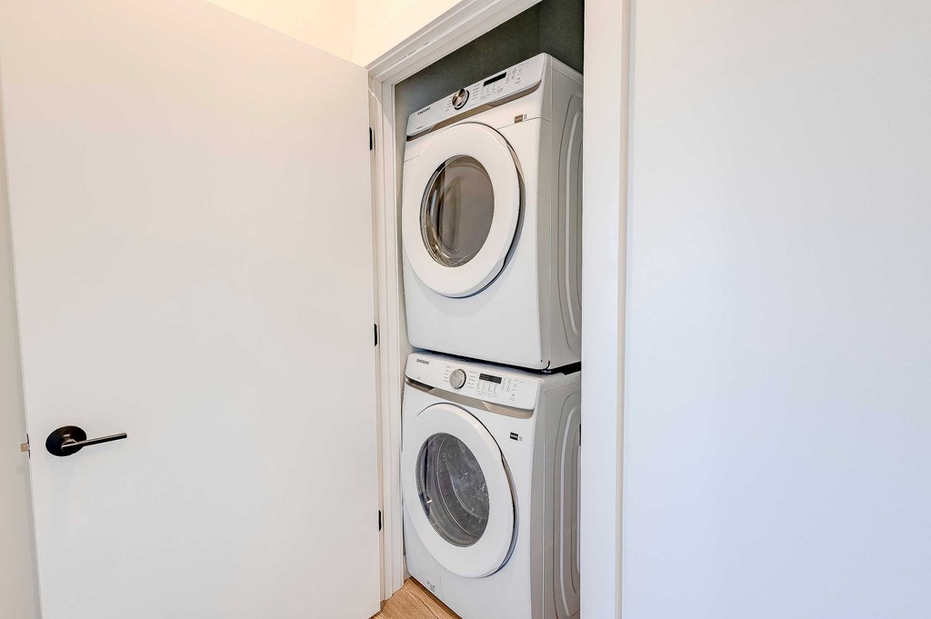 A white door opens to a small laundry room with a washer and dryer.