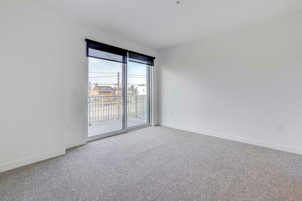 A room with a carpeted floor and a sliding glass door.