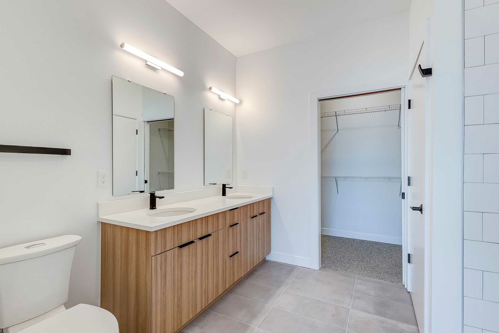 A bathroom with a white tub, sink, and wooden cabinets.