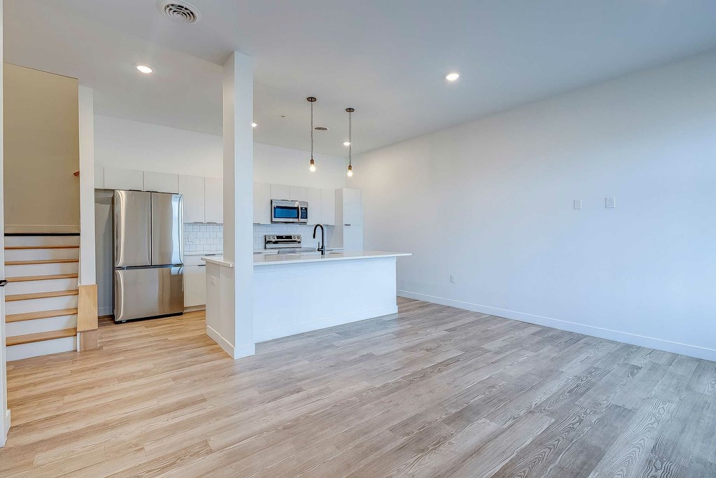 A kitchen with a refrigerator, microwave, and oven.