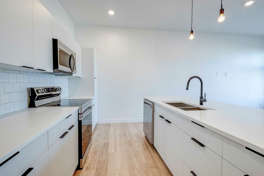 A kitchen with white cabinets and a wooden floor.