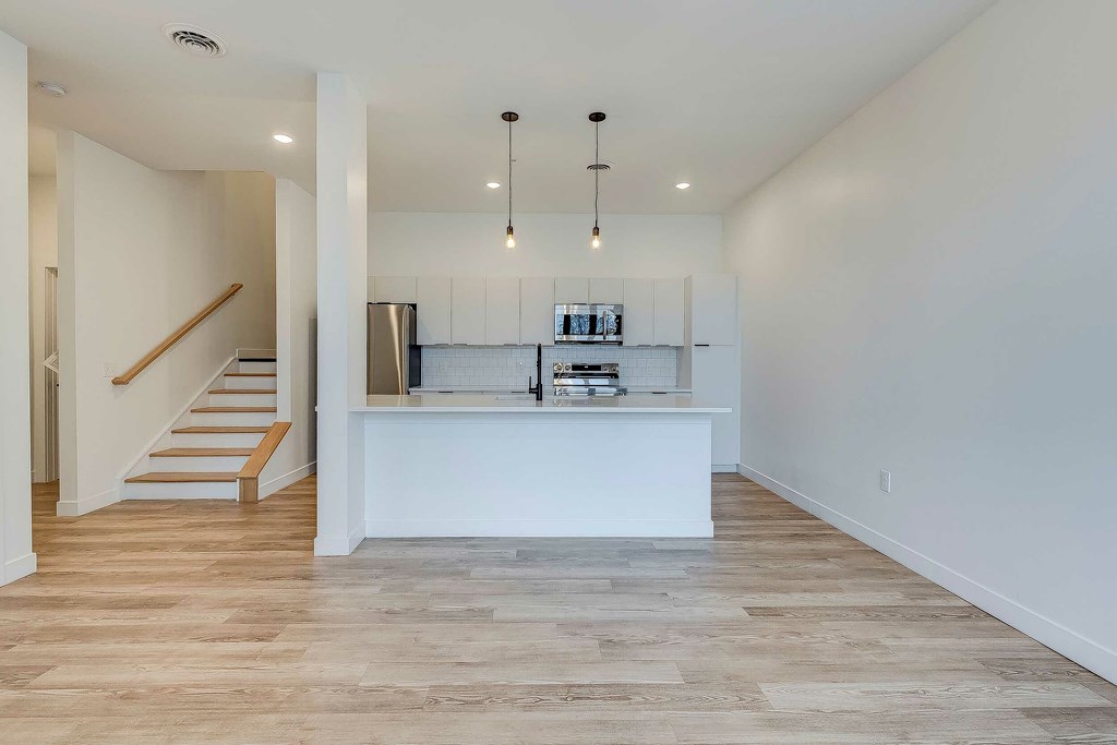 A kitchen with a white counter and wooden floors.