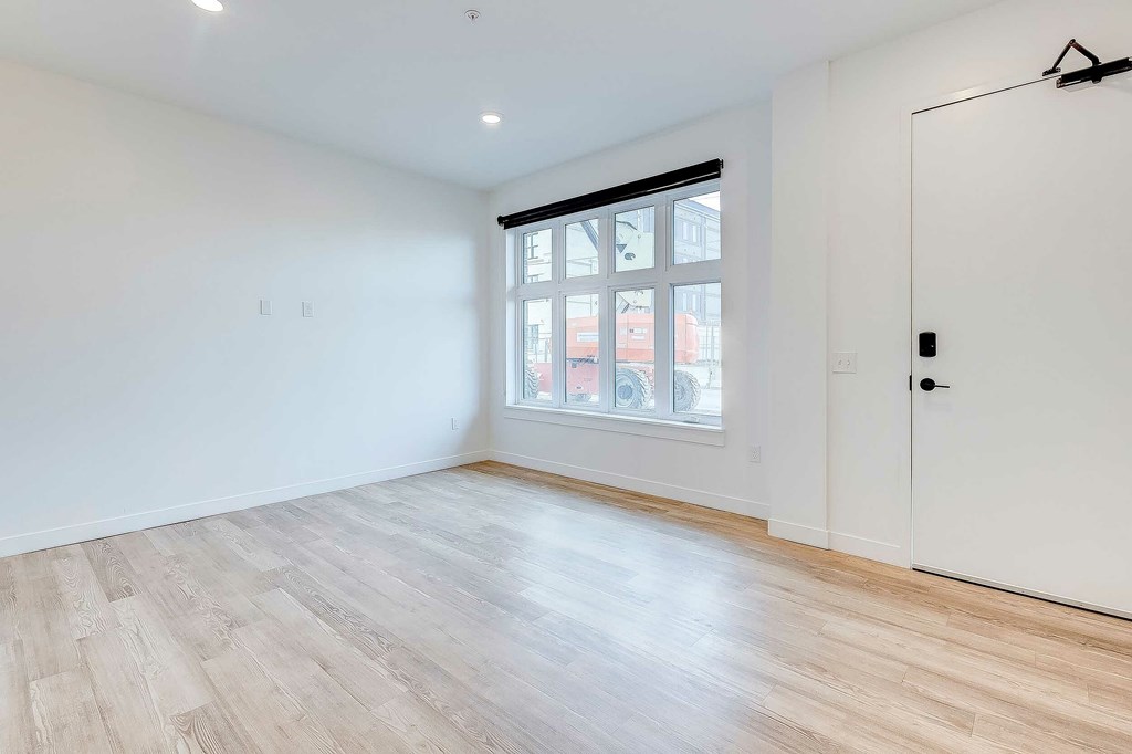 A room with a white door and a window with a view of a building outside.