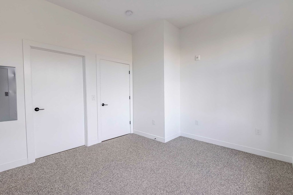 A room with white walls and a grey carpet.