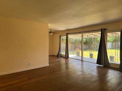 A room with wooden floors and sliding glass doors leading to a garden.