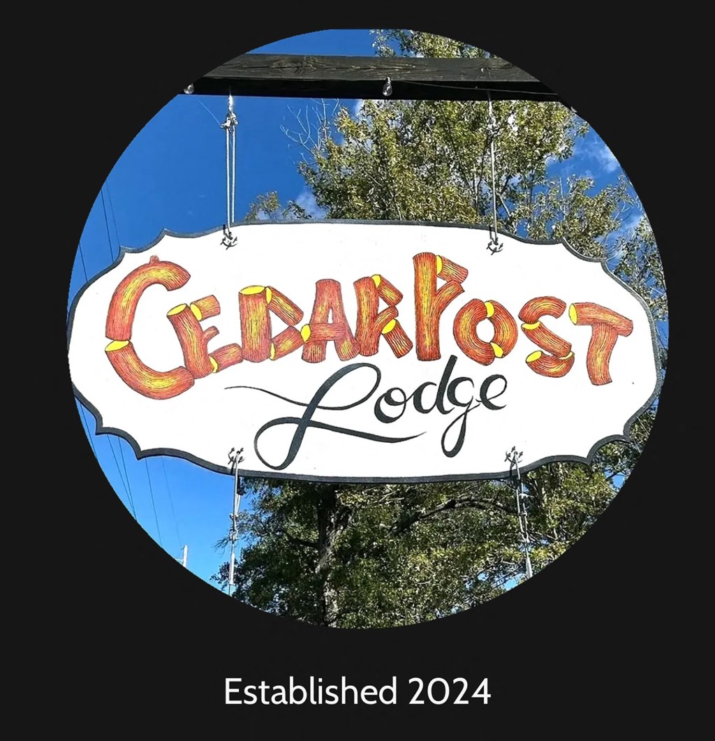 A sign that says Cedarpost Lodge is hanging from a pole.