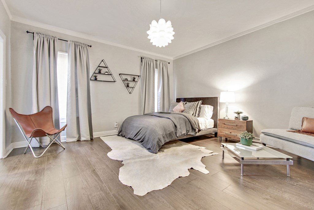 A bedroom with a bed, a chair, and a rug.