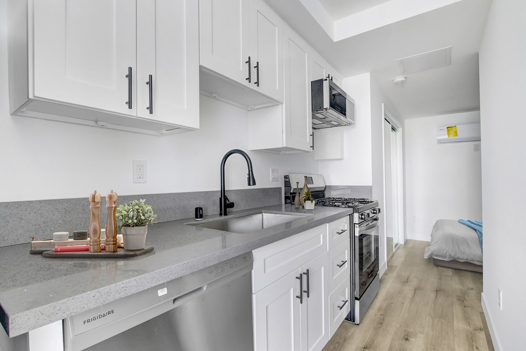 A kitchen with white cabinets and a grey countertop.