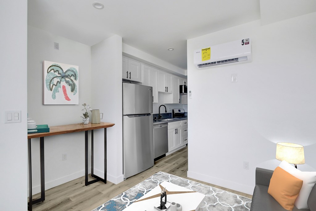 A kitchen with a refrigerator, a table, and a painting on the wall.