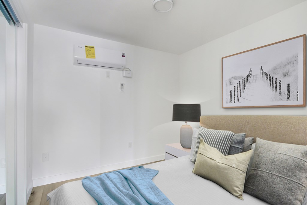 A bedroom with a bed, nightstand, lamp, and a painting on the wall.