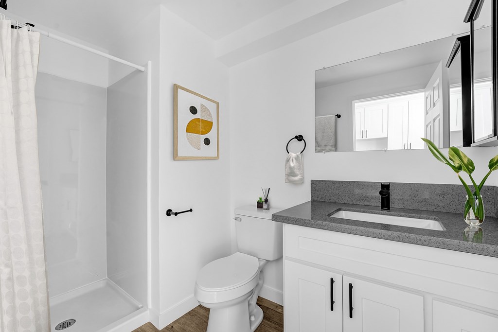 A white bathroom with a toilet, sink, and mirror.
